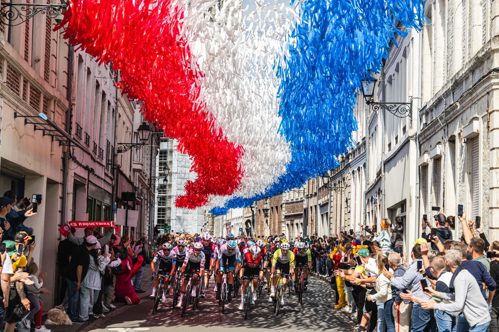 Tour de France peloton rolls through town decorated with French flags