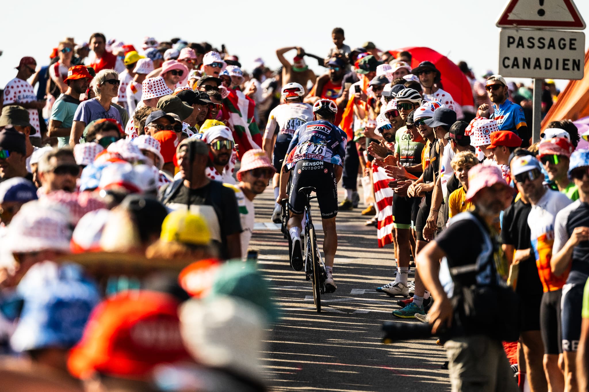 Cyclist in polka dot jersey surrounded by fans at Tour de France