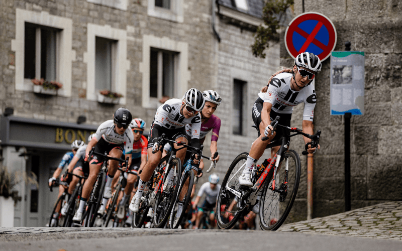 Cyclists in a road race, climbing a cobbled street.