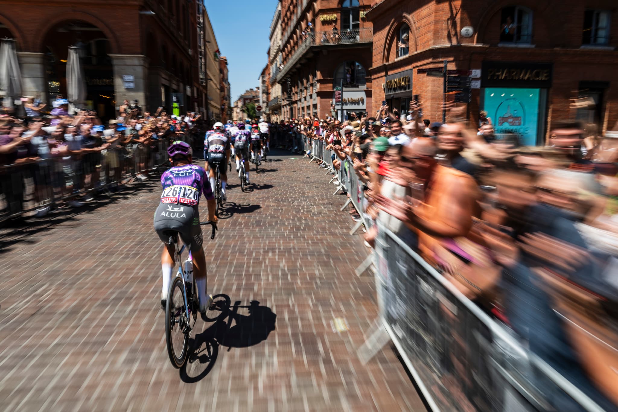Peloton racing through Barcelona, Jayco AlUla team visible