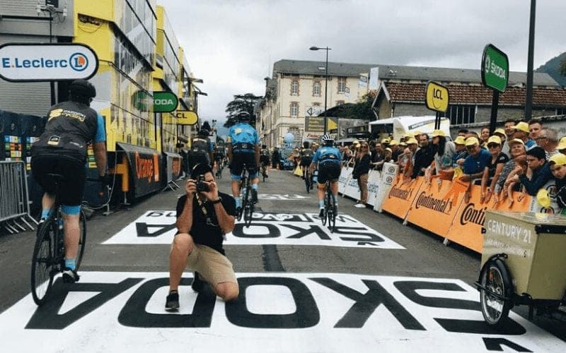 Cyclists racing on road with Skoda markings, photographer kneeling