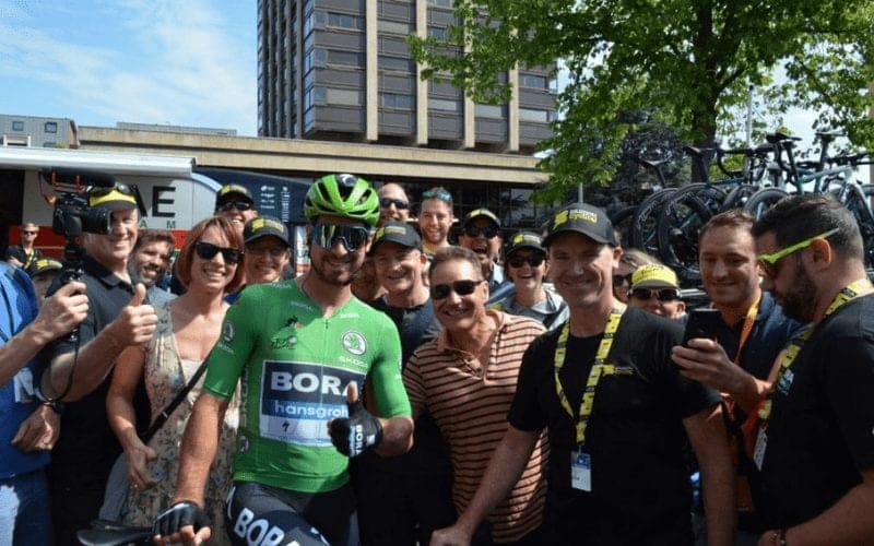 Bora-Hansgrohe rider in green jersey poses with fans.
