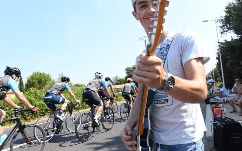 Cyclists pass roadside musician