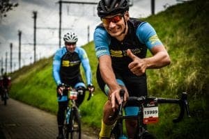 Cyclists on a paved path, one giving a thumbs up