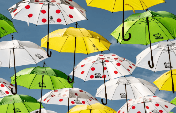Umbrellas in polka dot, yellow, green and white against blue sky