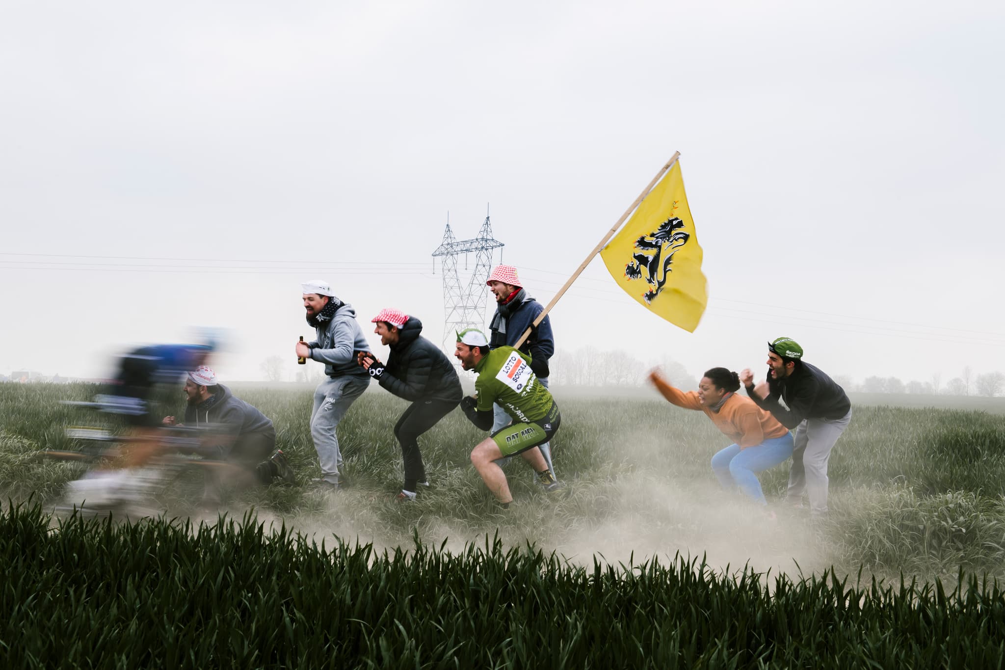 Cyclists racing past fans with a Flanders flag, 2019